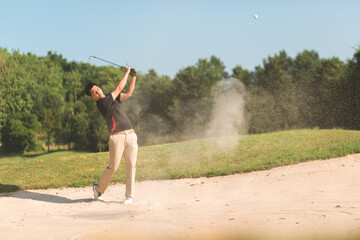 Golfers male exploding sand for a golf ball out of a bunker. concept healthy care and strengthens...