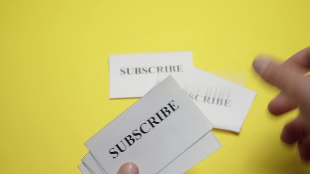 a man leafing through tickets with the inscription Subscribe on a colored surface	