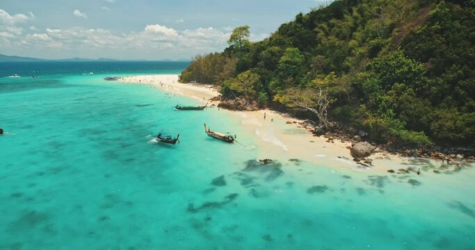 Travel to Thailand paradise tropic island. Boat tour to Phi Phi Leh. Turquoise water, traditional wooden long tail boats, white sand beach. Wild landscape. Exotic summer vacation. Drone flight aerial