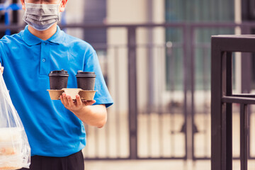 Asian young delivery man in blue uniform wearing face mask making grocery service giving rice food...