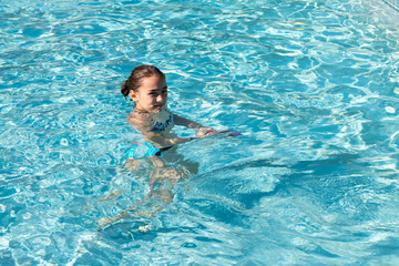 Young girl looking at camera in the swimming pool. Kid outdoor activities. Summer concept. Happy childhood.