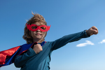 Kid having fun outdoors in super man cloak. Boy playing superhero. Success and winner concept.