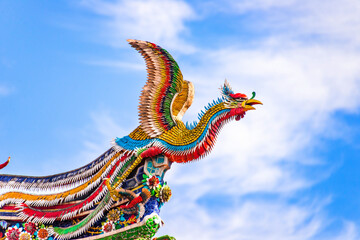 Fototapeta na wymiar Beautiful Phoenix flying on the decorative tile roof in Chinese temples. Colorful roof detail of traditional Chinese temple