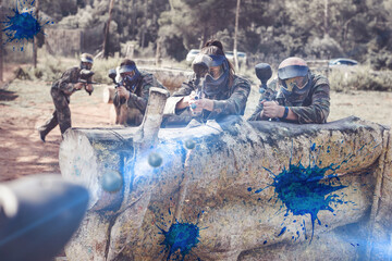 Paintball players aiming and shooting with their guns at an opposing team outdoors
