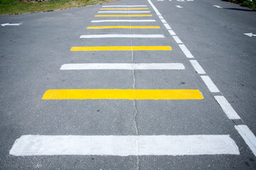 Obraz premium Pedestrian crossing, white-yellow stripes on a road.