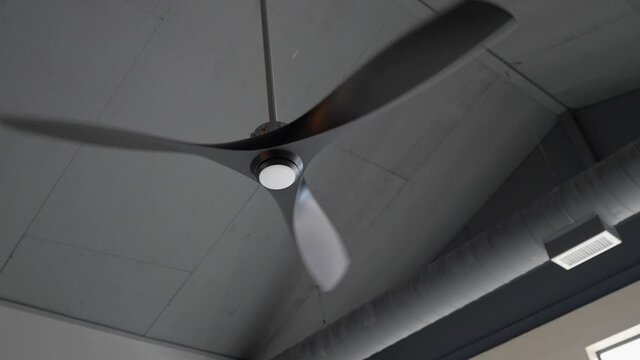 This video shows a modern industrial style fan rotating in the ceiling of a contemporary building.