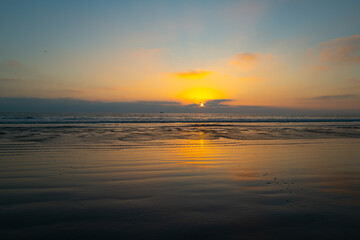 Obraz na płótnie Canvas Calm sea with sunset sky and sun through the clouds over. Ocean and sky background, seascape.