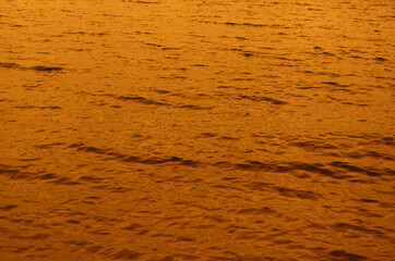 The texture of seawater during sunset or sunrise. Orange-gold li