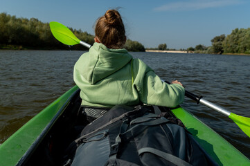 Girl in front of the boat. The girl is rowing with an oar. The view of the girl from behind.