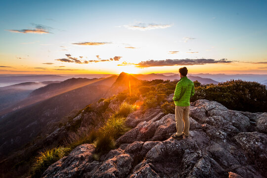 Hiker watching mountain sunset from the east peak of Mount Barney