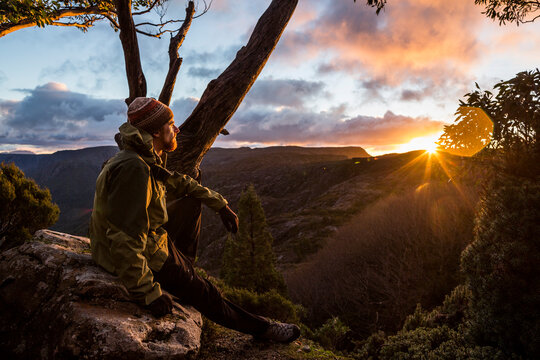 A hiker watching the sunset beside the Overland Track