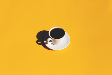 Cup and plate of coffee with shadow of sun on yellow terracotta background
