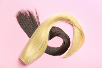 Strands of brunette and blonde hair on color background