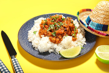 Plate with tasty chili con carne, rice, lime and sombrero hat on color background, closeup