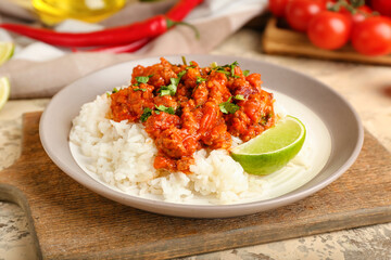 Plate with tasty chili con carne, rice and lime on table, closeup