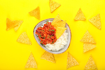 Bowl with tasty chili con carne, rice and nachos on color background