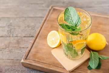 Glass of tasty ice tea with lemon on wooden background
