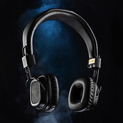 Audio headphones on a black background. Black headphones and blue smoke. Advertising photo of...