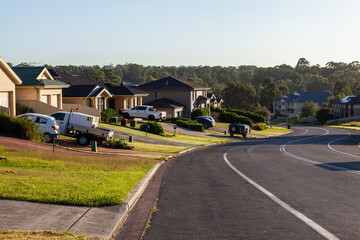 Cars parked in driveways of houses beside suburban road