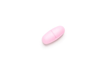 One single pink pill on white background, multivitamin tablet or dietary supplement