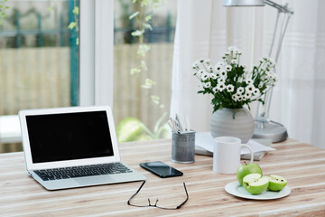 Fototapeta na wymiar Laptop with empty screen, smartphone, glasses and plate with green apples for snacks