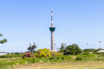 Obraz premium Remote photo Lighthouse and traffic control tower cargo ship sailing as national flag picture with blue sky clouds a background. symbol or landmark port of Lamchabang Thailand