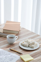 Cup of coffee and popcorn bars on office desk next to docuemnt with charts and stack of books