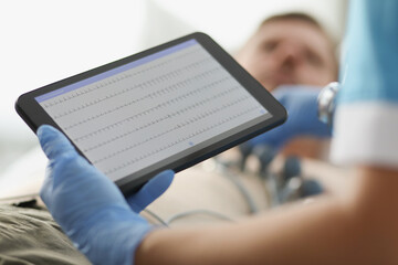 Cardiologist examines patient electrocardiogram on tablet closeup
