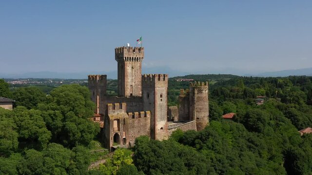 Aerial view of the Italian historic castle Castello Scaligero on a hill, view of the Ponte Visconteo bridge and the Mincio river. Castle Scaligero in Valeggio sul Mincio, Verona, Italy.