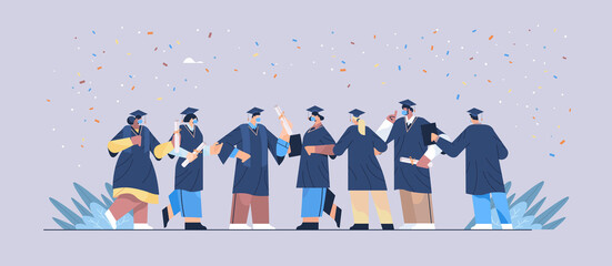 Obraz premium graduated students in masks happy graduates celebrating academic diploma degree education university certificate
