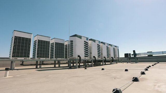 An air conditioning system of two rows of air conditioners is located on the roof of the business center. The camera is shooting from below. Nice sunny day. 4K