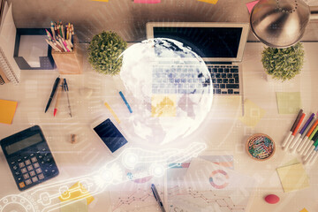 Double exposure of map hologram drawing over study table background with computer. Concept of international network. Top view.