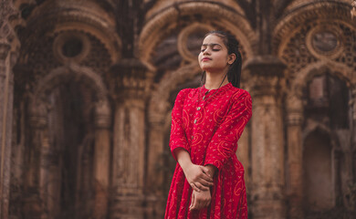 Beautiful Indian girl in traditional dress standing peacefully in front of the monument - obrazy, fototapety, plakaty