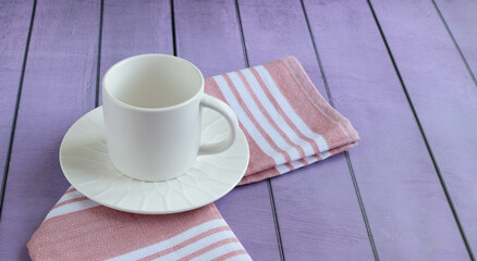 White empty cup and saucer, kitchen cotton napkin on colored background, close-up. Concept of breakfast, afternoon tea. Top and side view.