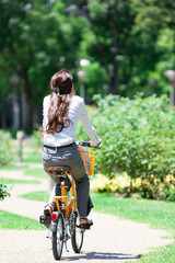 Fototapeta premium 自転車に乗るビジネスウーマンの後姿