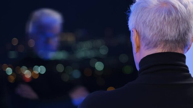 Old retired mentally ill gentleman in turtleneck sweater looking at his doubling reflection. Elder graying businessman by the window. Grey haired male person. Senior gaffer man with white shaved face.