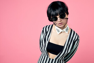 Young woman wearing trendy fashion outfit during coronavirus outbreak. Style look including protective stylish face mask and glasses. Studio shot.