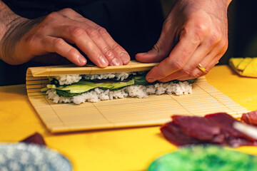 Sushi chef turns nori sheet with filling i