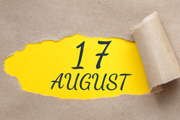 august 17. 17th day of the month, calendar date.Hole in paper with edges torn off. Yellow background is visible through ragged hole.Summer month, day of the year concept