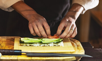 Cook hands making Japanese sushi roll.