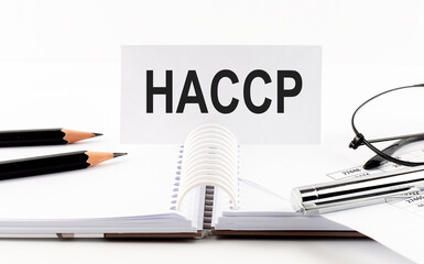 Text HACCP on paper card,pen, pencils, glasses,financial documentation on table - business concept