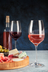 Wine, cheese, charcuterie and olives. Italian antipasti buffet with glasses of rose and red wine with blue cheese on a dark background with a place for text