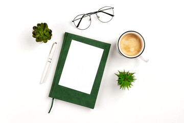 Light postcard mockup for design presentation on a white workplace with coffee, notebook, pen, glasses and potted flowers. Business background with copy space.