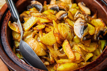 Potatoes with mushrooms baked in a pot. Close-up, selective focus