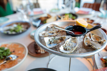 platter of fresh organic raw oysters on ice at restaurant. Oysters on the server table