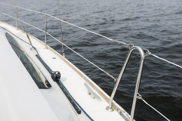 Boat trip on the river. Details about the sailing yacht. In the summer, we go by boat. A white yacht with full sails. Leisure, sports, recreation theme. Close-up view of the metal railing.