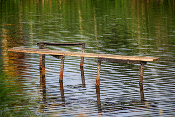 A dilapidated bridge on the river bank on a summer day