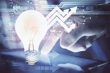 Double exposure of man's hands holding and using a digital device and bulb hologram drawing. Idea concept.