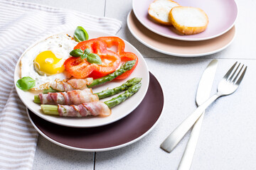 Toasted egg with asparagus, bacon and bell pepper on a plate. Delicious and healthy breakfast.