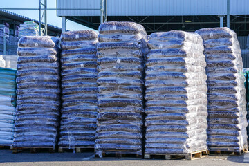Pallets stacked with large transparent plastic film bags of soil peat